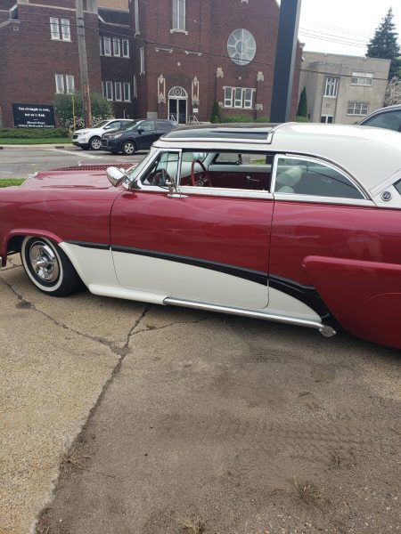 Red and white classic car outside the shop